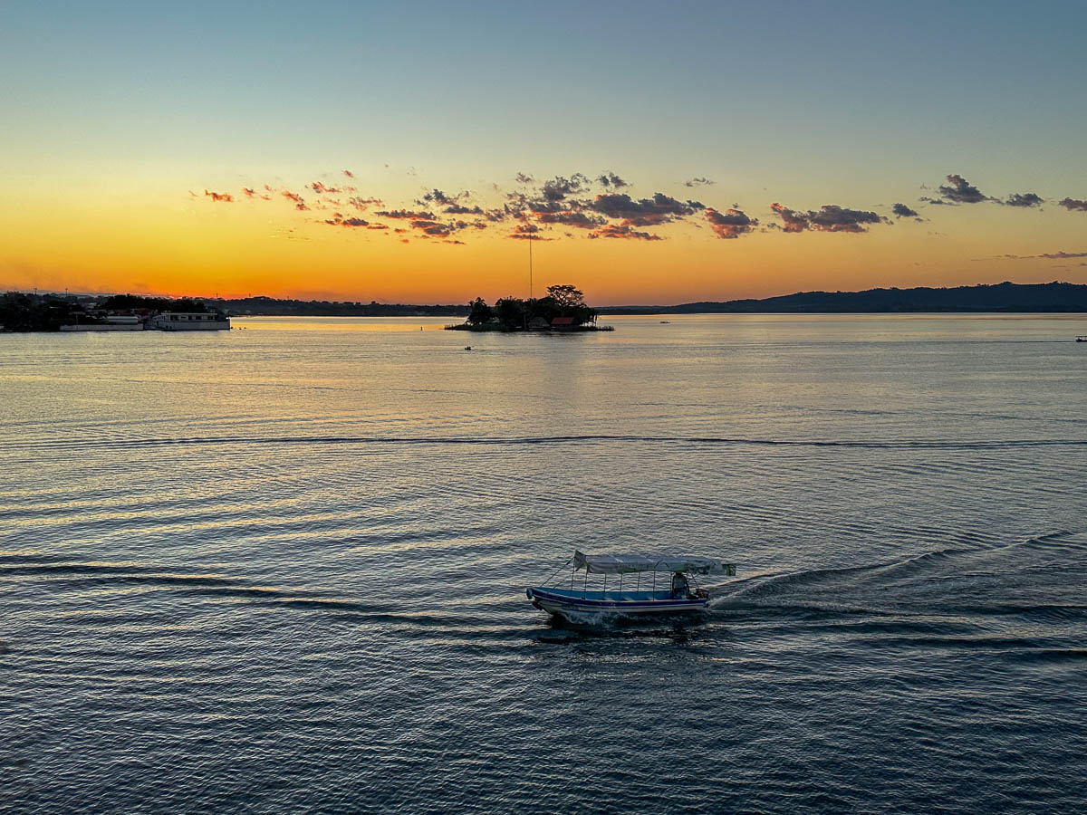 Boat cruising across Lake Pete at sunset in Flores, Guatemala