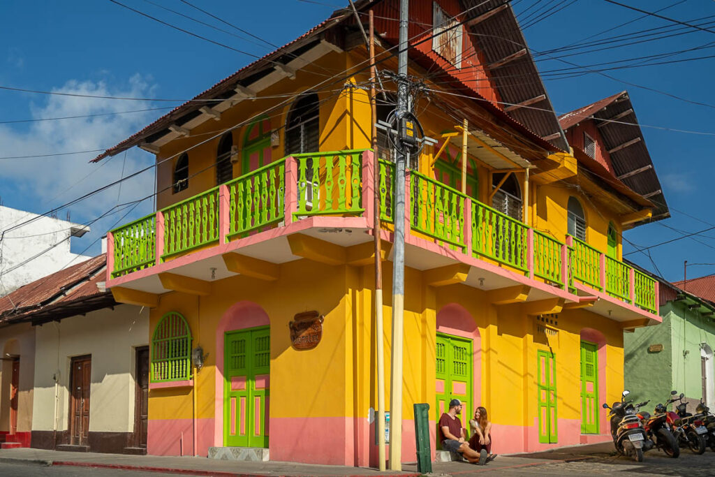 Couple sitting in front of a colorful building in Flores, Guatemala