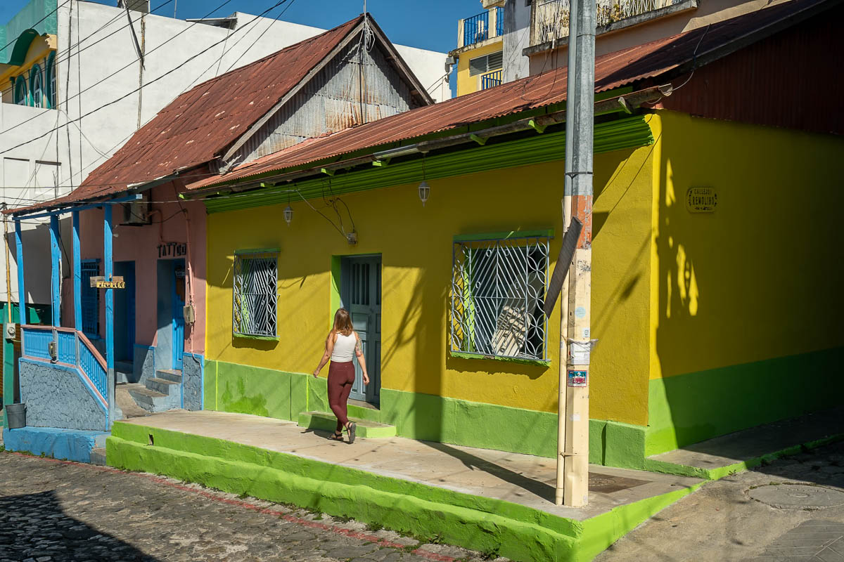 Woman walking past colorful buildings in Flores, Guatemala