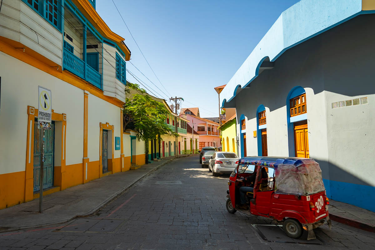 Tuk-tuk driving down streets through colorful buildings in Flores, Guatemala