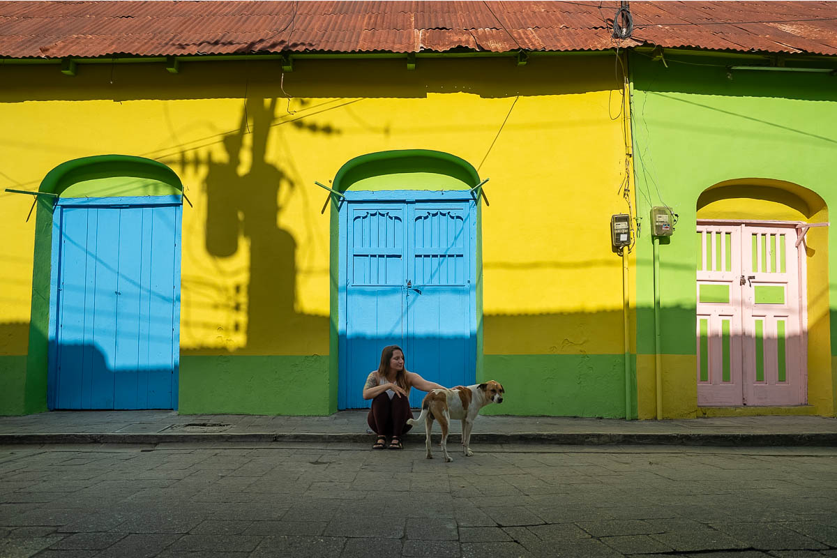 Woman petting a dog in front of a colorful building in Flores, Guatemala