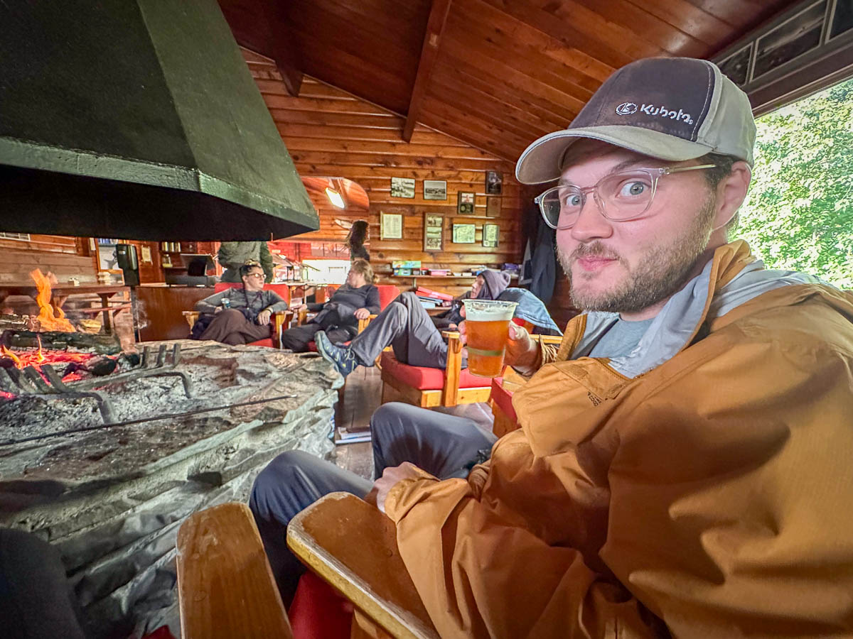 Man holding a beer next to a fireplace  in Brooks Lodge in Katmai National Park in Alaska