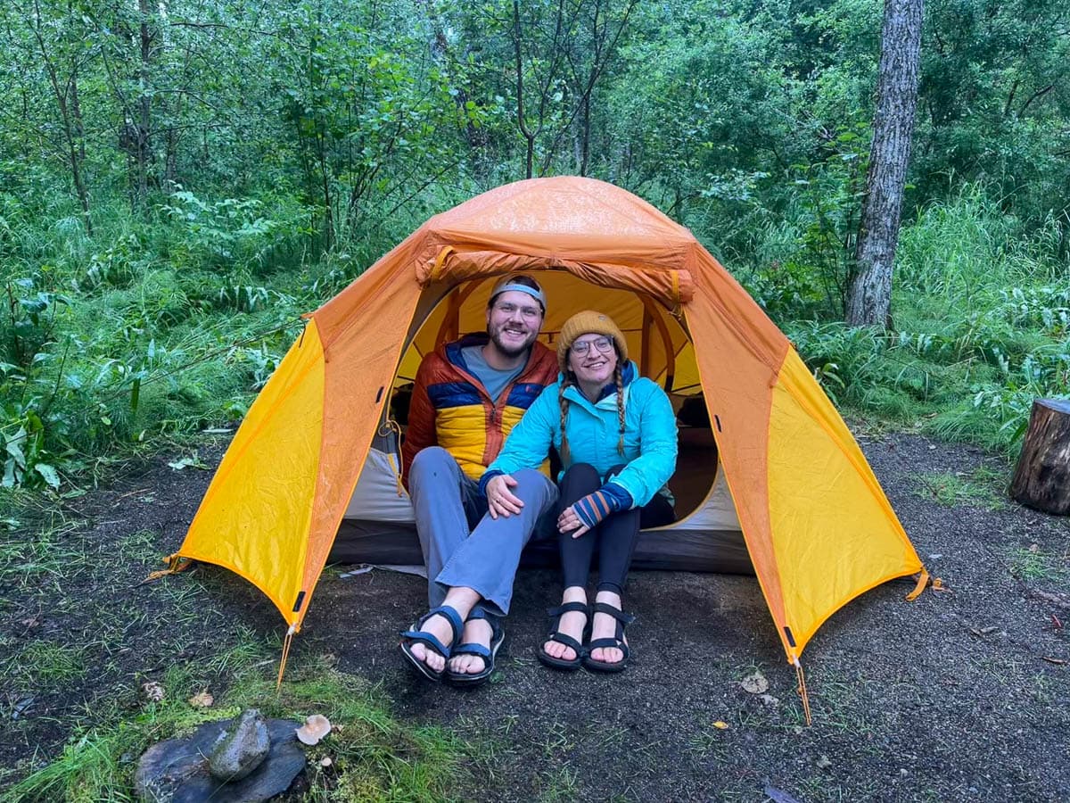 Smiling couple sitting in their tent in Brooks Camp Campground in Katmai National Park in Alaska