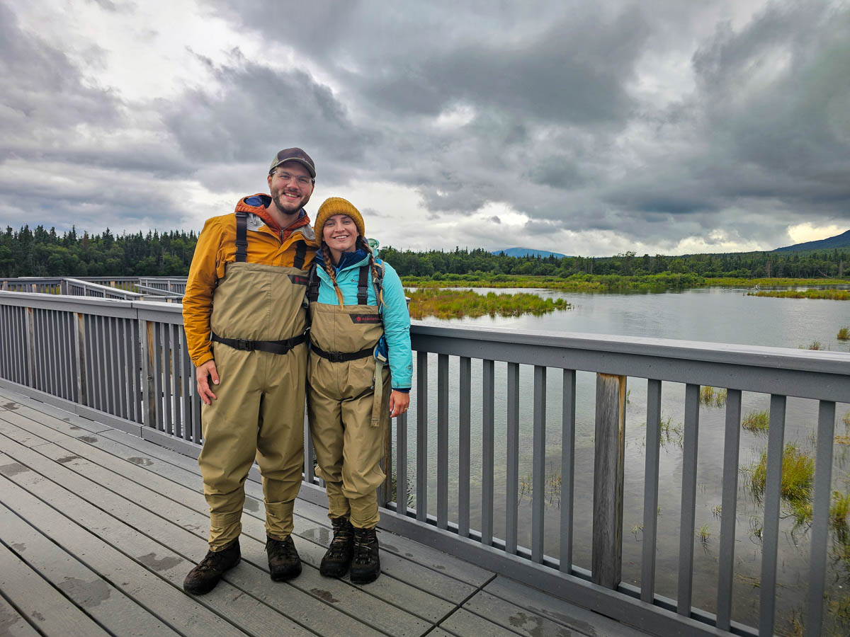 Couple wearing waders on a wooden platform along the Brooks River in Katmai National Park in Alaska