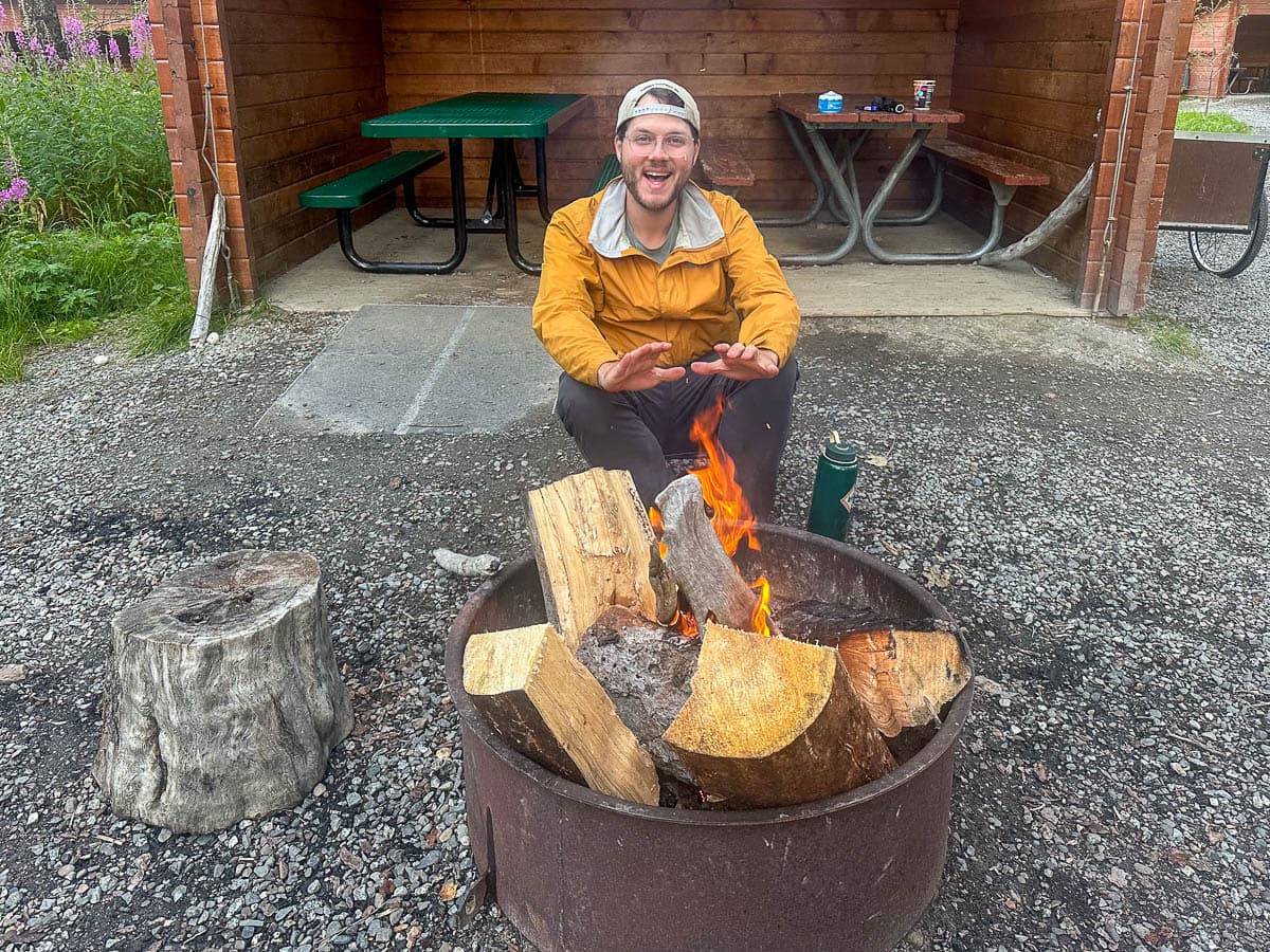 Man warming his hands on a campfire at the Brooks Camp Campground in Katmai National Park in Alaska