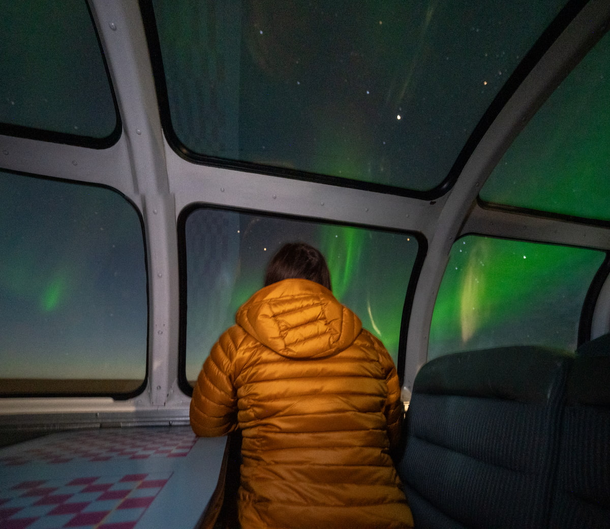 Woman sitting in the dome car of the Via Rail train, watching the Northern Lights, to Churchill, Manitoba, Canada