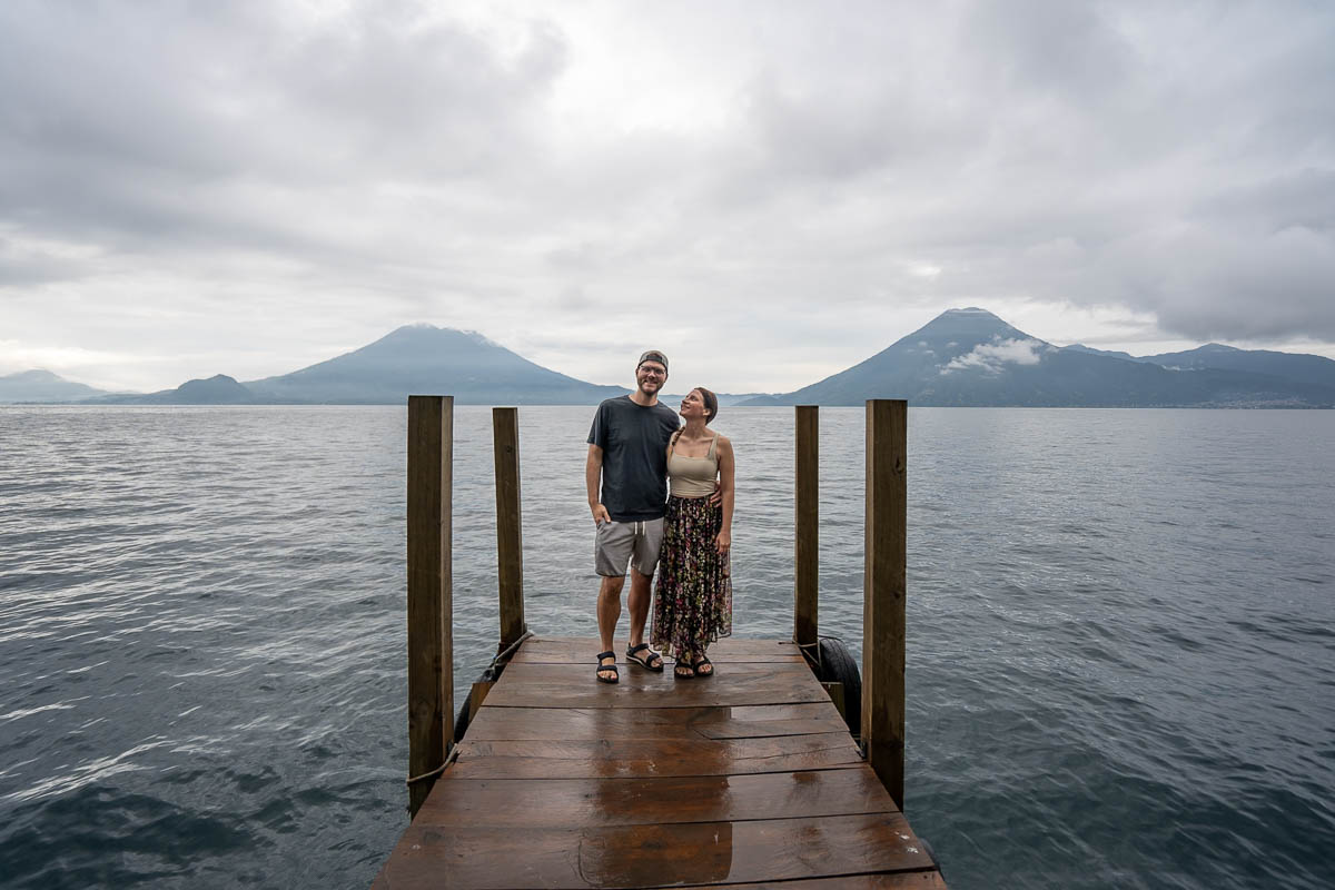 Couple standing on a dock with volcanoes in the background at Casa del Mundo in Guatemala