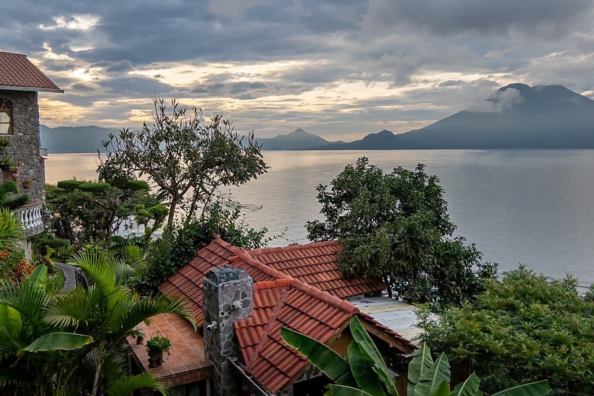 View over rooftops at Casa del Mundo with volcanoes in the background at Lake Atitlan, Guatemala