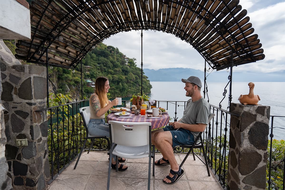 Couple eating breakfast at a table with Lake Atitlan in the background in Casa del Mundo in Guatemala