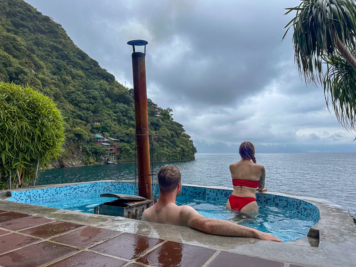 Couple sitting in a wood-fired hot tub overlooking Lake Atitlan at Casa del Mundo near Jabilito, Guatemala