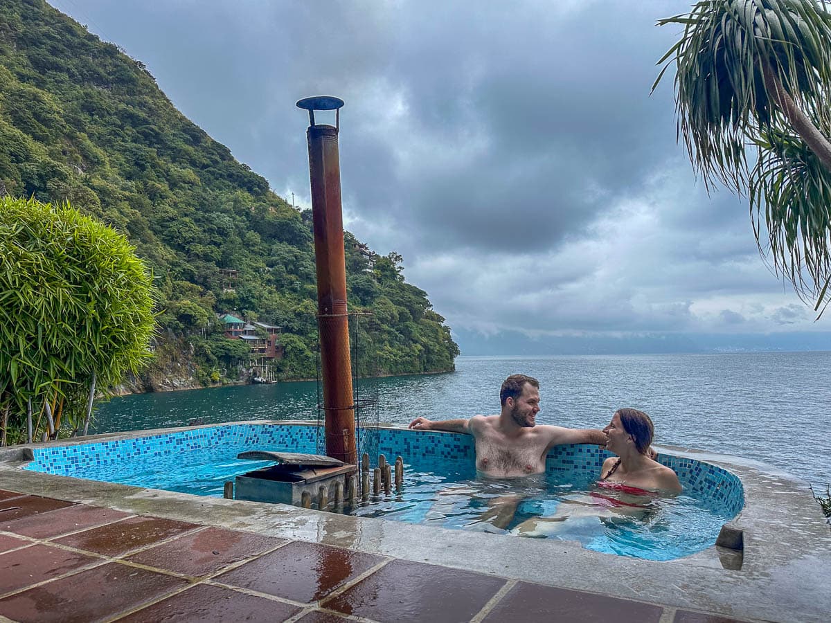 Couple sitting in a wood fired hot tub overlooking Lake Atitlan at Casa del Mundo in Guatemala