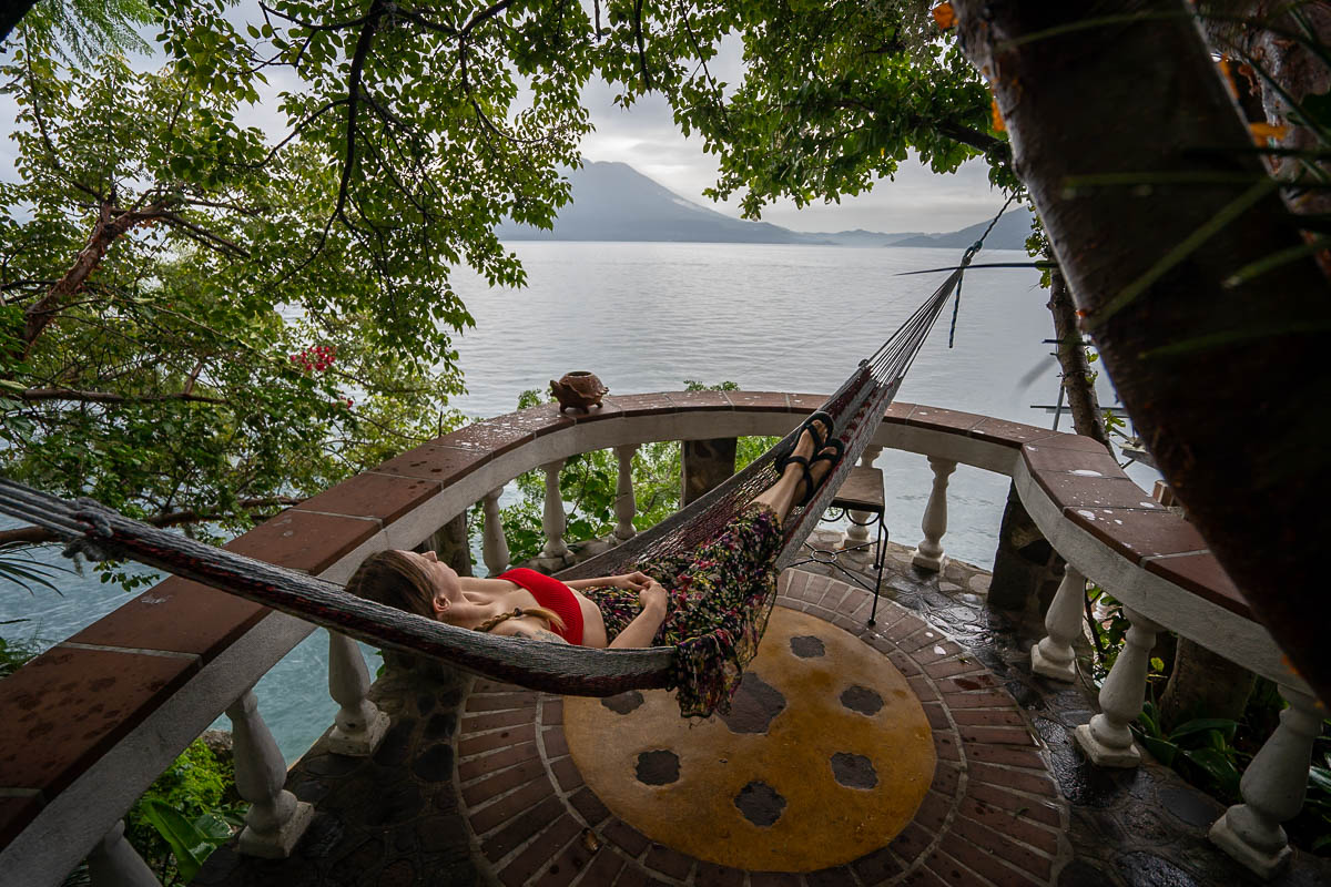 Woman laying in a hammock overlooking a volcano and Lake Atitlan at Casa del Mundo in Guatemala