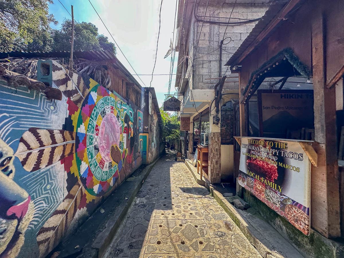 Narrow street with colorful murals and restaurants in San Marcos, Guatemala