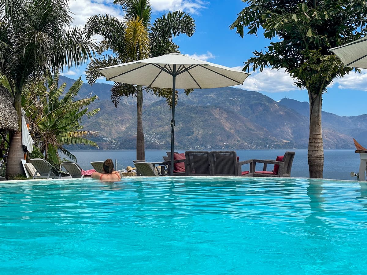 Woman leaning against the edge of a pool overlooking mountains and Lake Atitlan at Sababa Resort in San Pedro, Guatemala