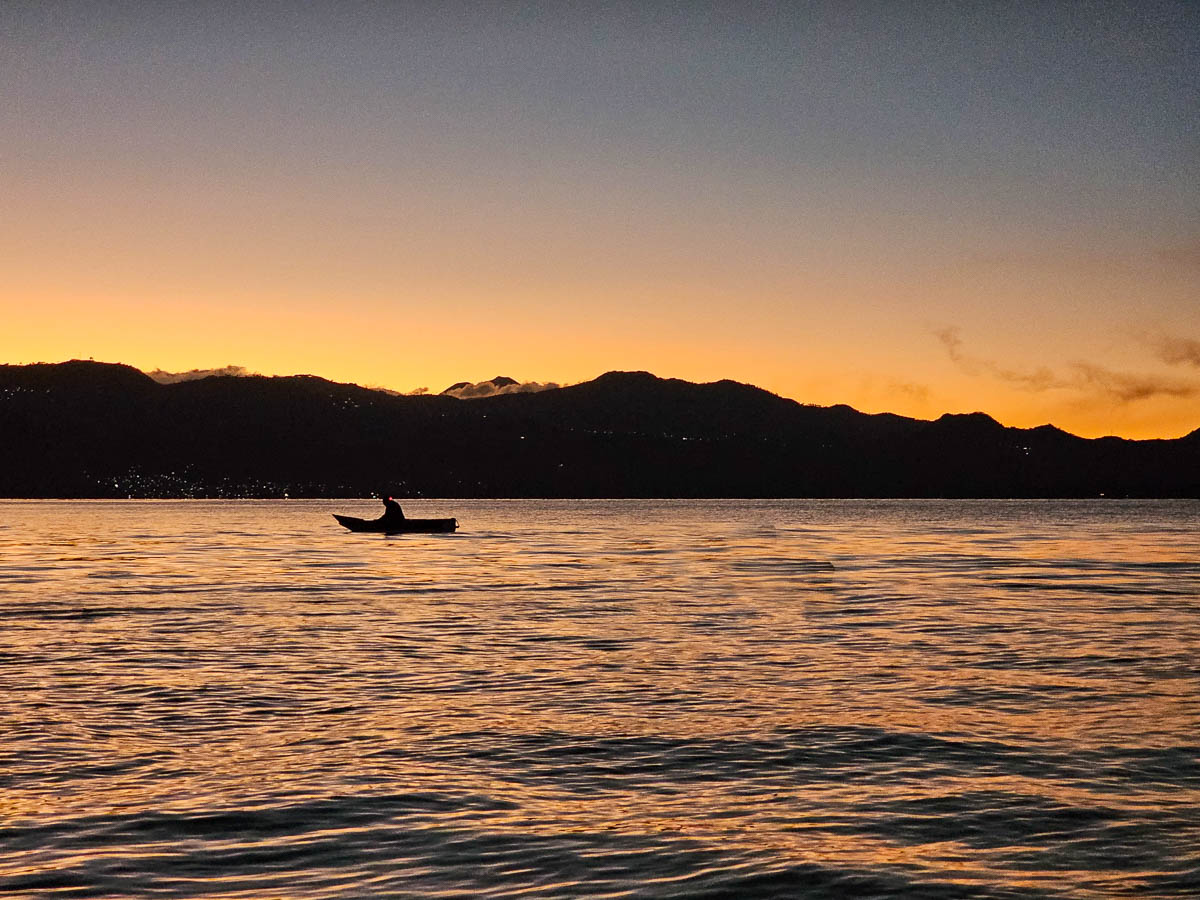 Person kayaking at sunrise in Lake Atitlan in Guatemala