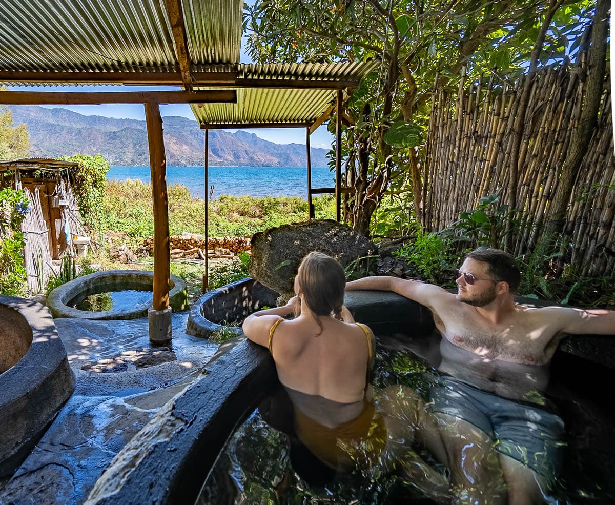 Couple soaking in a hot tub in Los Termales in San Pedro, Guatemala with mountains in the background