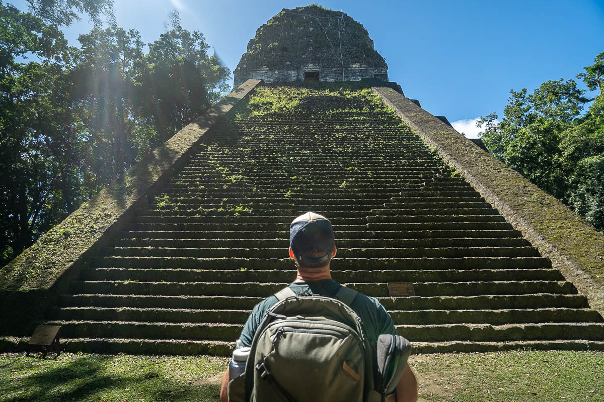 Man looking up steps at Temple V at Tikal National Park in Guatemala