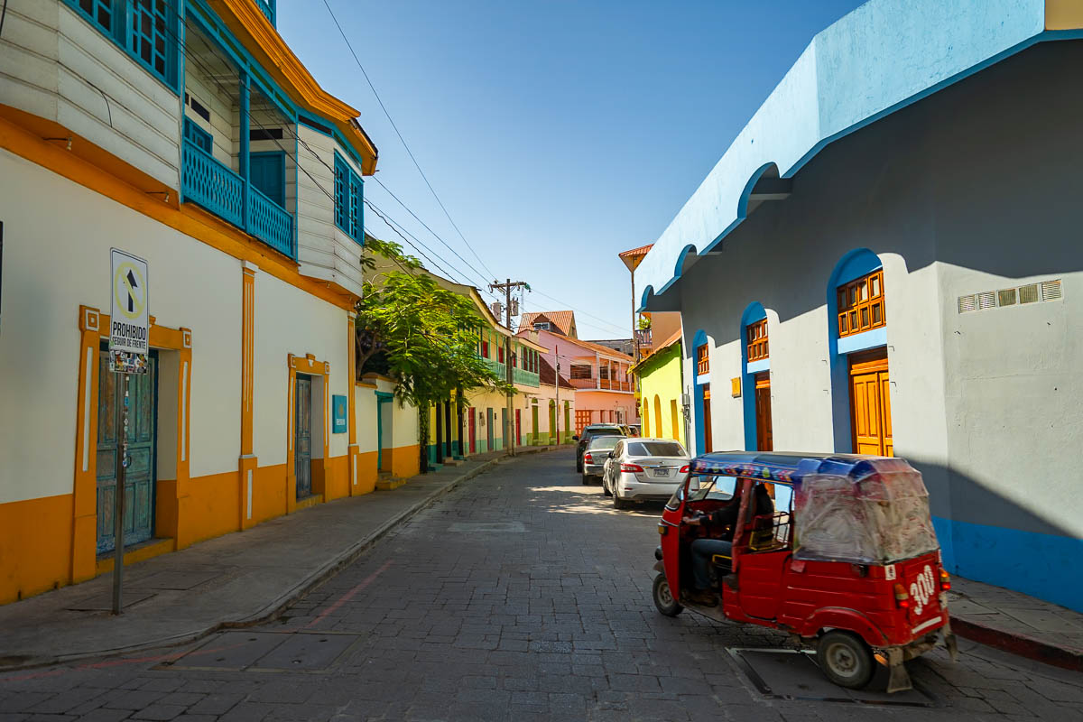 Tuk tuk driving past colorful buildings in Tikal, Guatemala