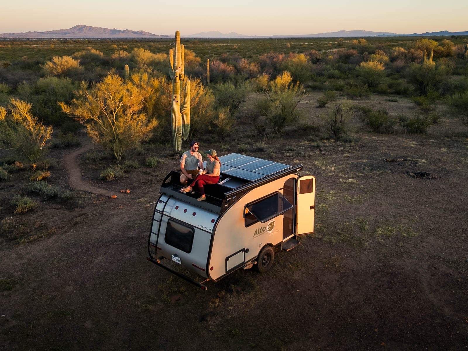 Couple sitting on top of a Safari Condo Alto F1743 Expedition next to saguaro cactuses in Tucson, Arizona