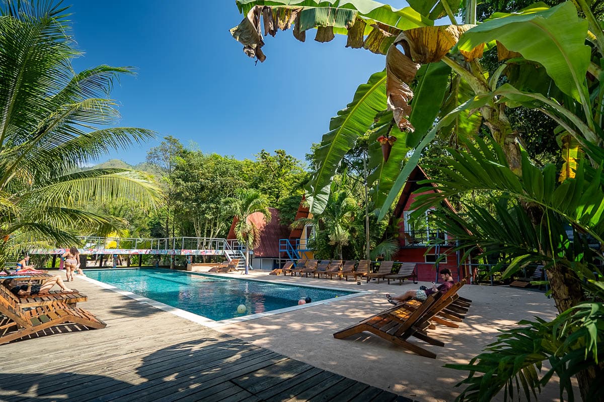 Pool surrounded by A-frame cabins and greenery at Greengos Hotel in Lanquin, Guatemala