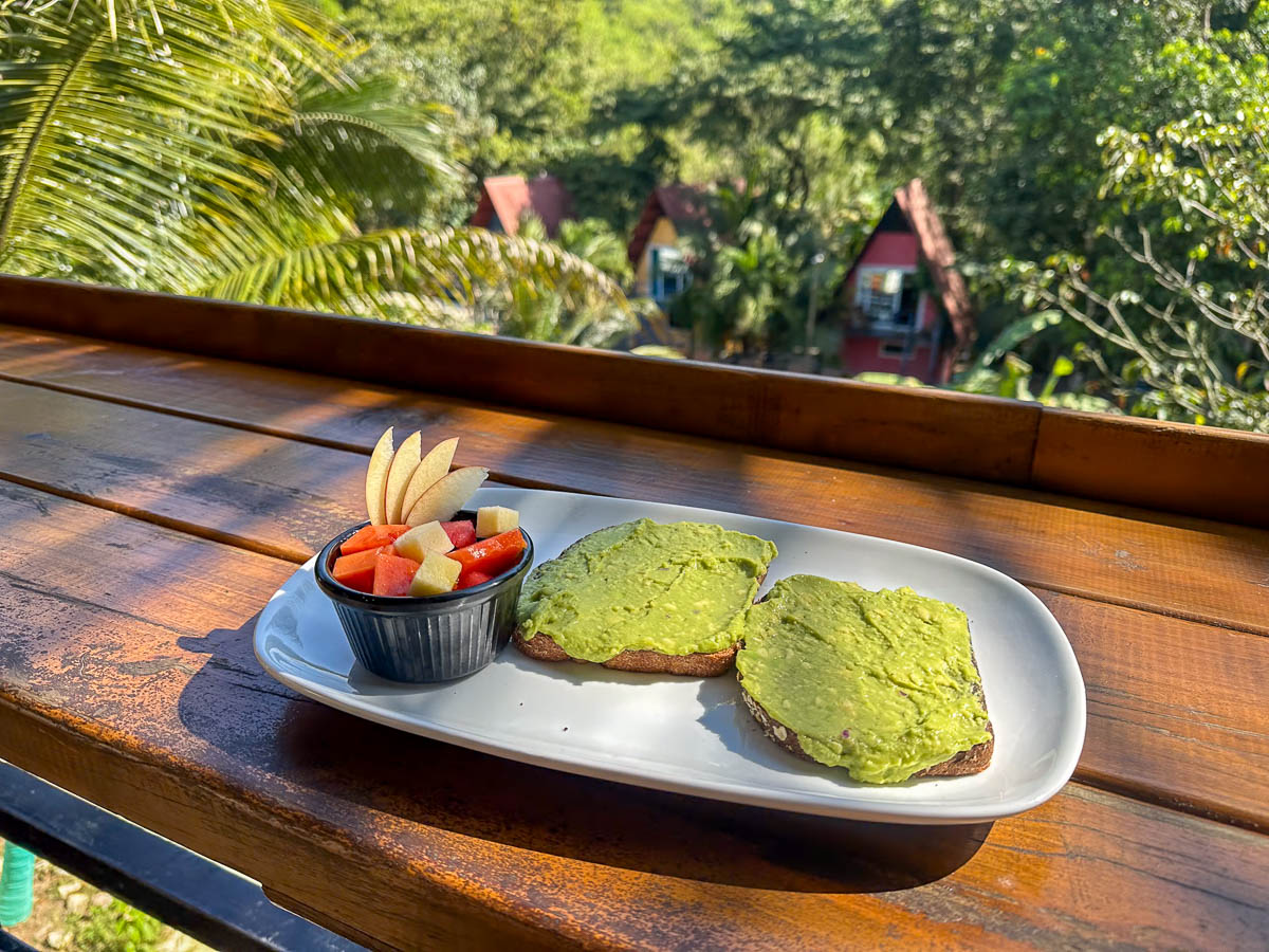 Avocado toast on a counter overlooking A-frame cabins at Greengos Hotel near Semuc Champey, Guatemala