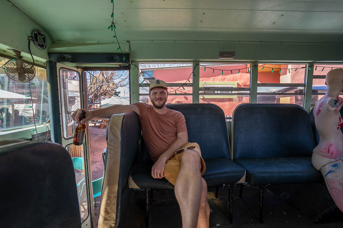 Man sitting on a school bus with a beer at Planet Marfa in Marfa, Texas