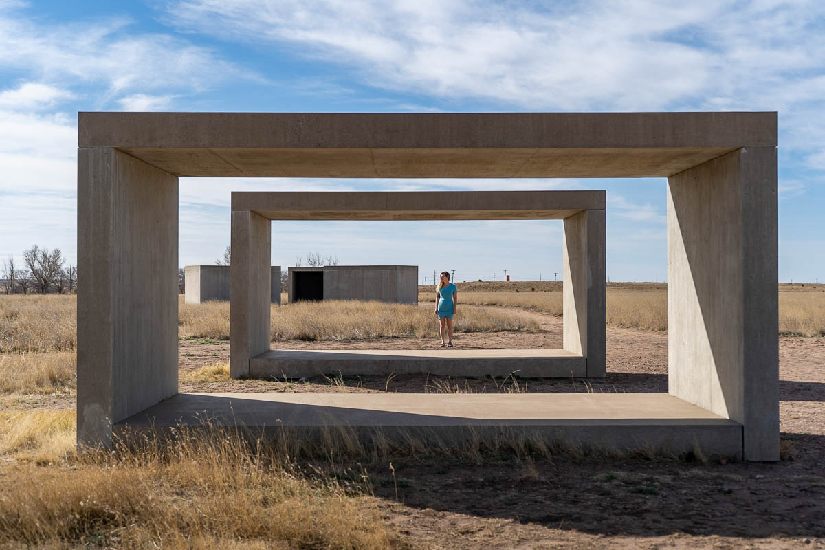 Woman standing by cement block art installations at the Chinati Foundation in Marfa, Texas