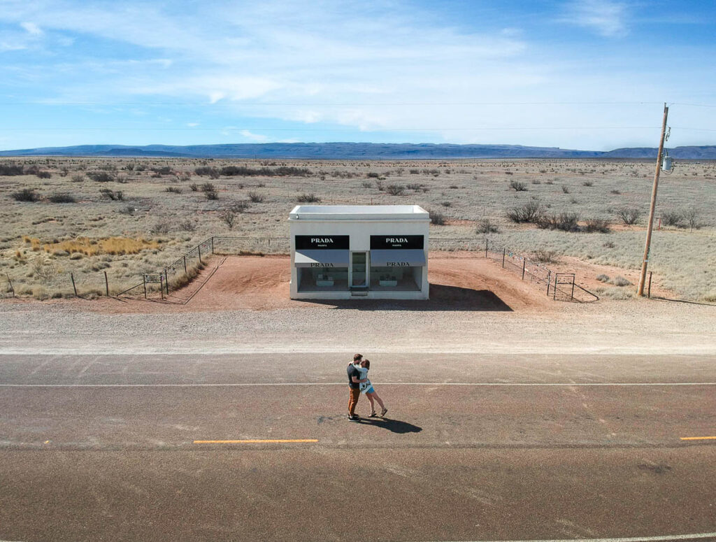 Couple embracing in front of the Prada Marfa art installation in Valentine, Texas