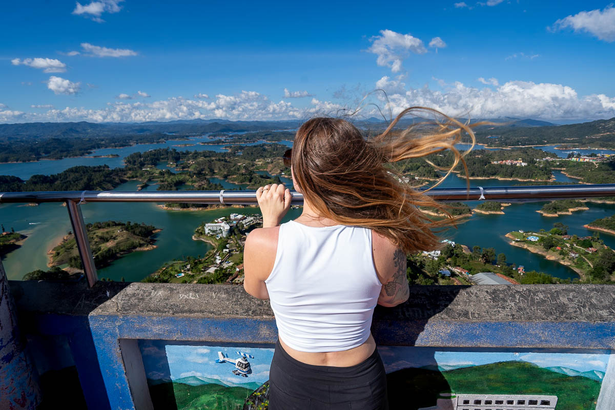 Woman looking over the railing at the Guatape-Penol Reservoir at the top of The Rock in Guatape, Colombia