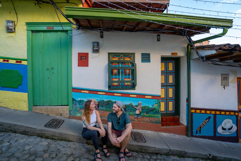 Couple sitting in front of colorful buildings with zócalos in Guatape, Colombia