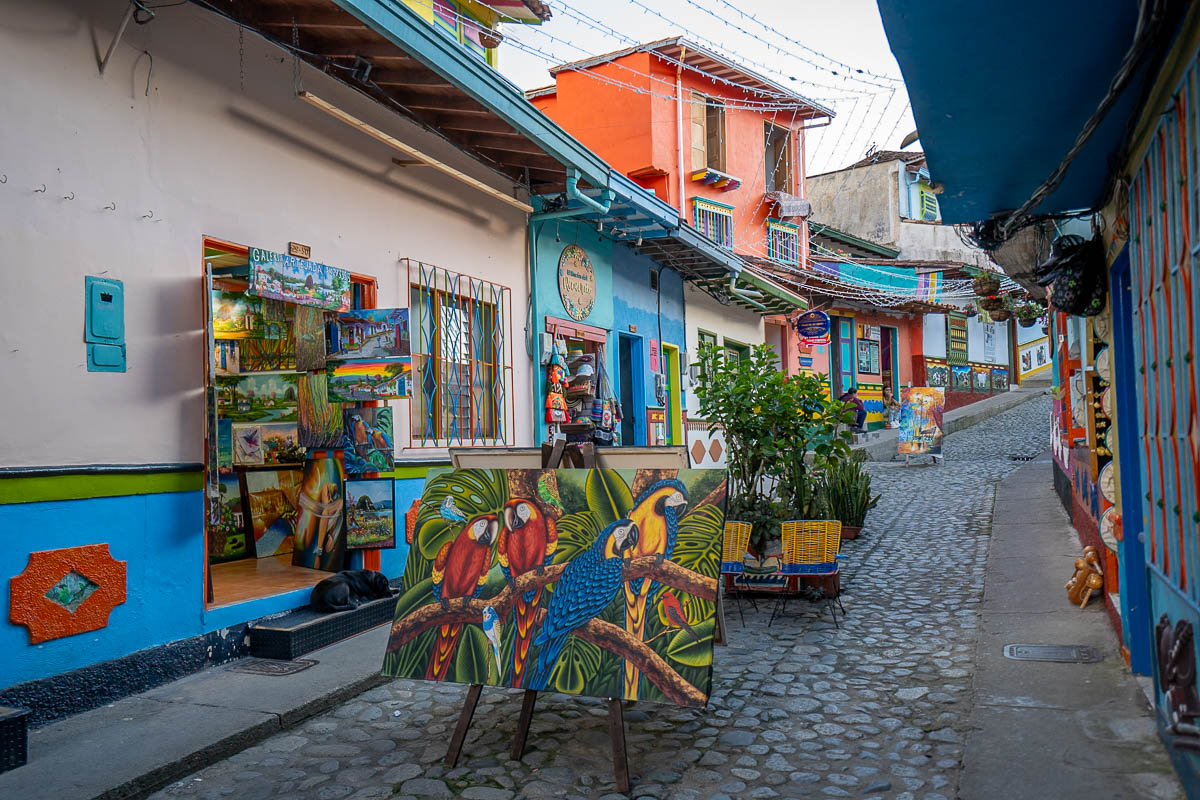 Artwork displayed in front of a store on a colorful cobblestone street in Guatape, Colombia