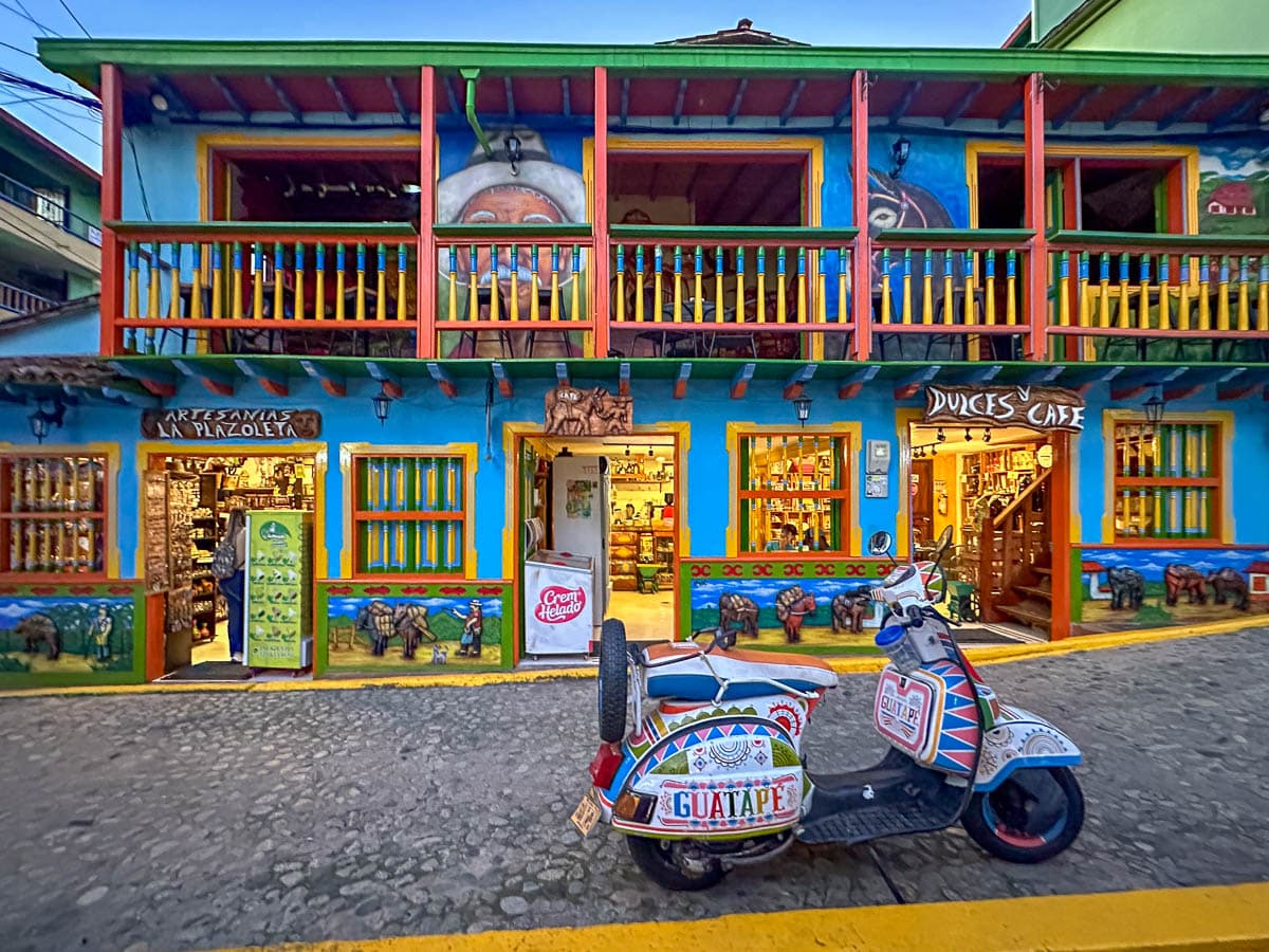 Scooter parked in front of a colorful building in Plaza del Zócalos in Guatape, Colombia