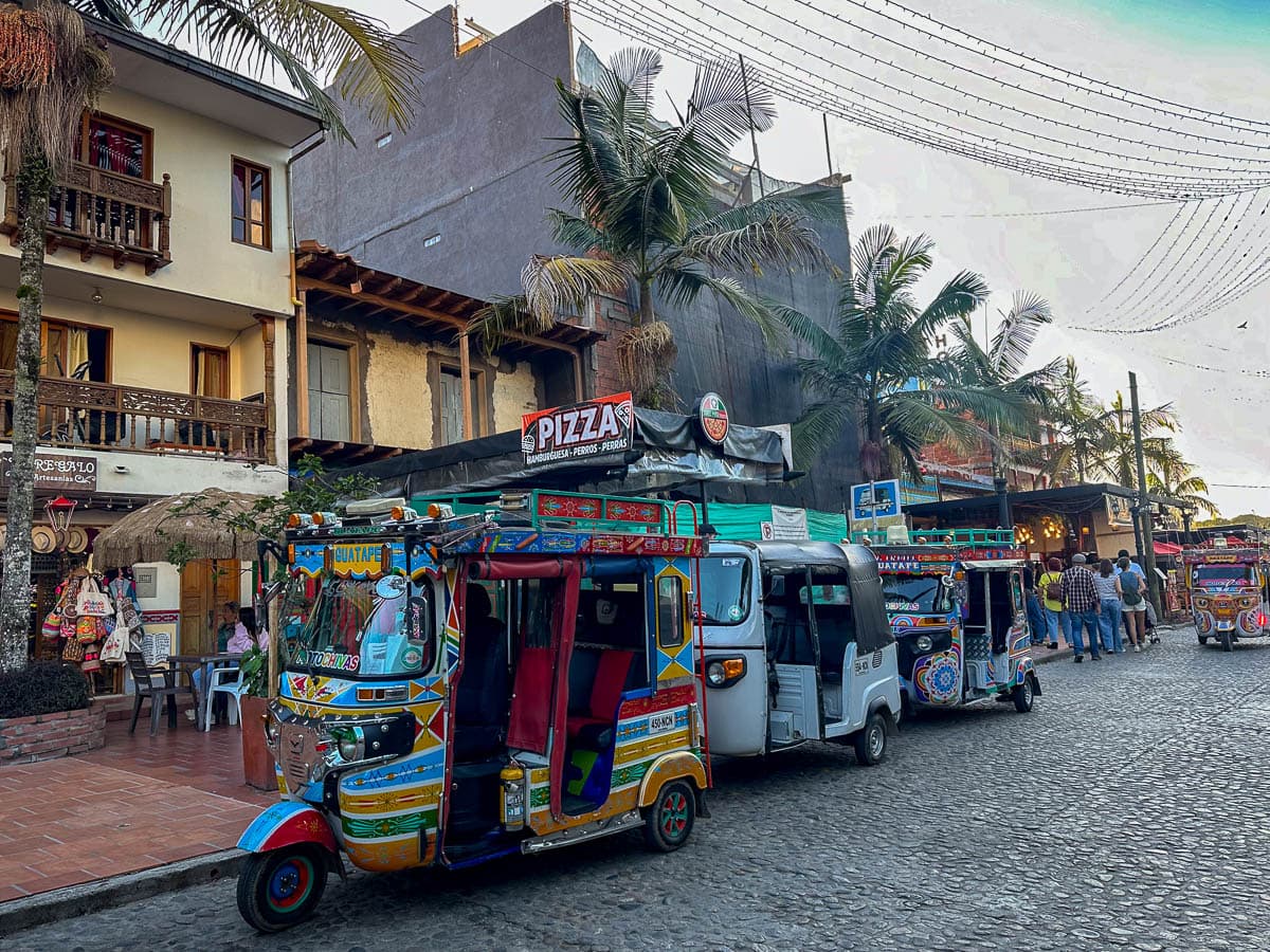 Tuk-tuks parked in front of stores on a cobblestone street in Guatape, Colombia