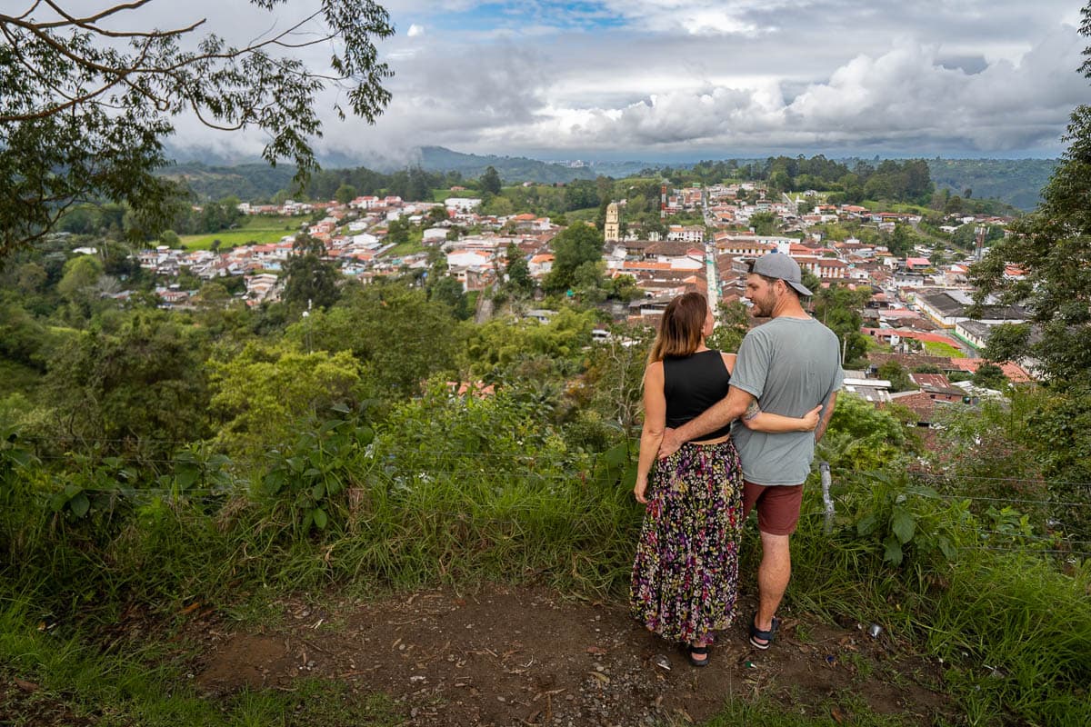 Couple standing at the Mirador de Saento, overlooking the buildings of Salento, Colombia