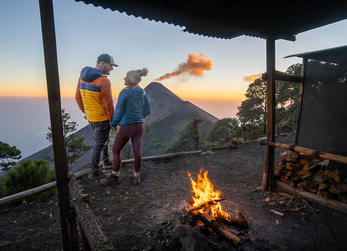 Couple holding hands in front of Fuego Volcano while it is erupting along the Acatenango hike in Guatemala