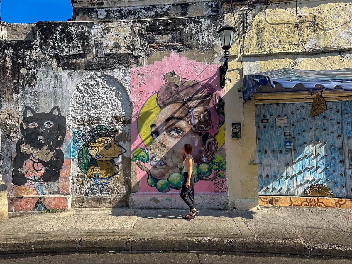 Woman walking past a colorful mural in the Getsamani neighborhood of Cartagena, Colombia