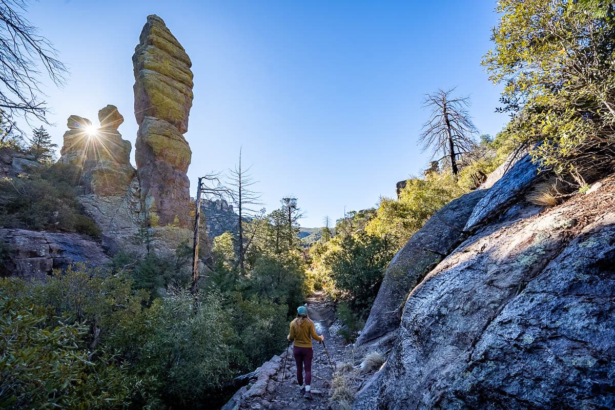 Woman walking along a hiking trails with rock formations in the background in Chiricahua National Monument in Arizona