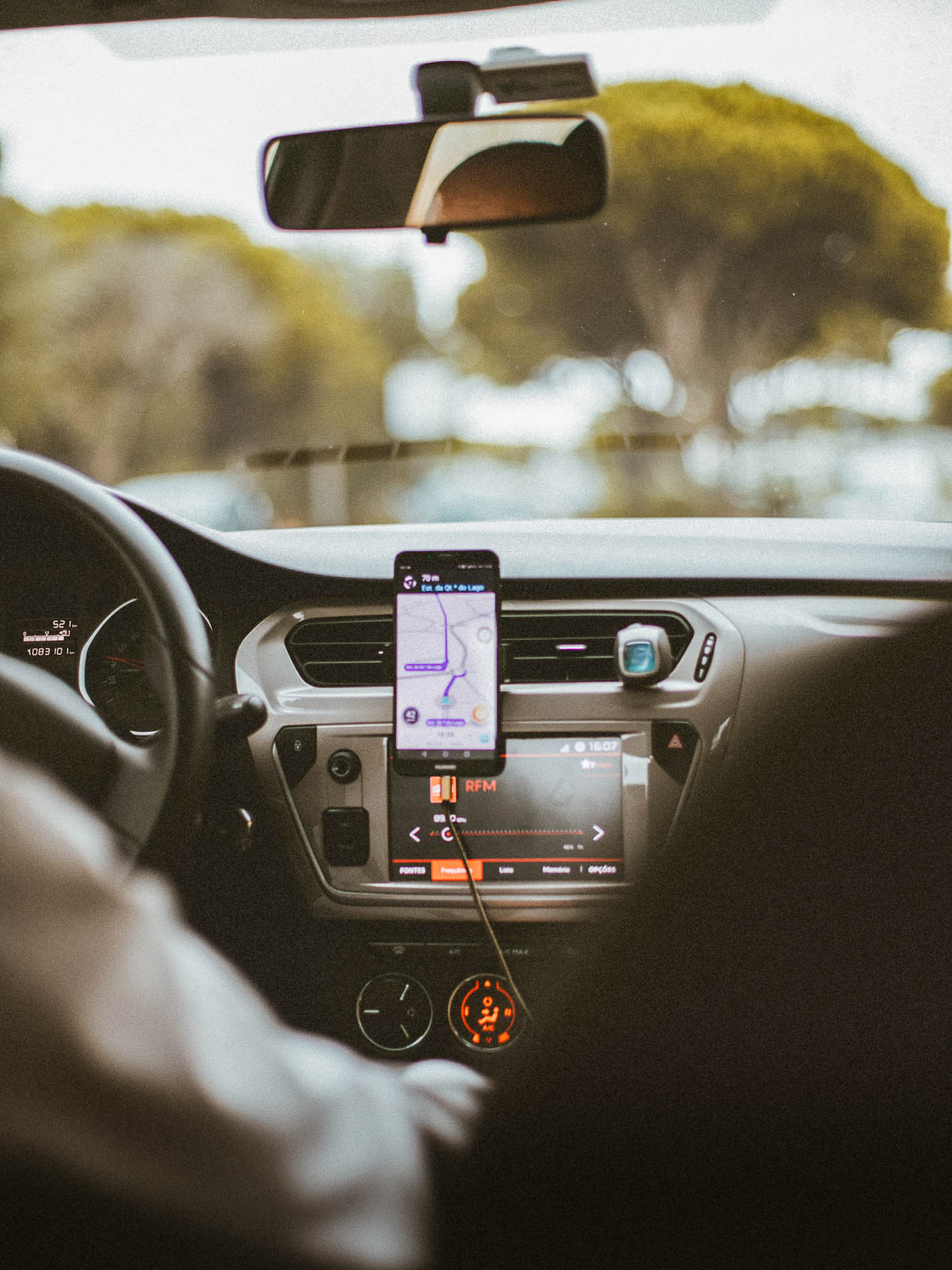 View of a cell phone on a dashboard of a car with a GPS app from the backseat of the car