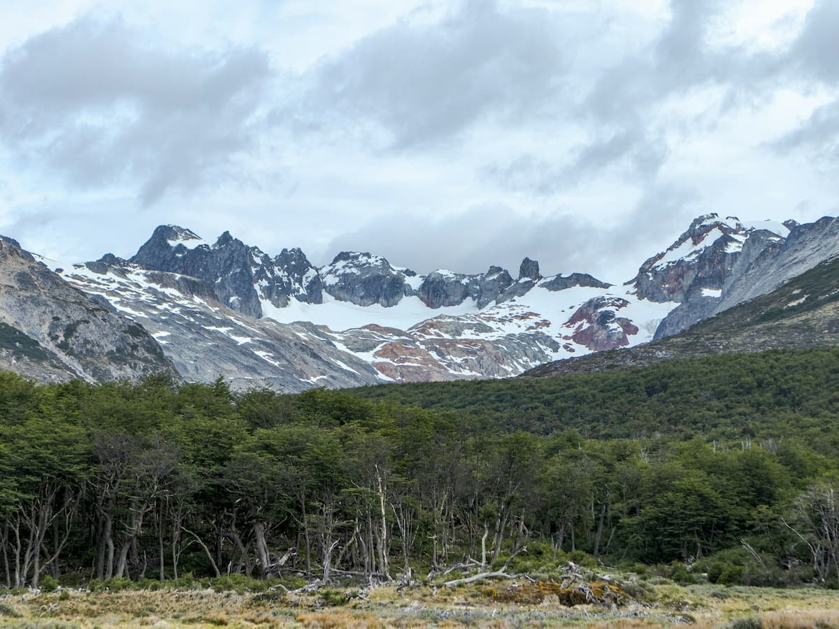 Snow-capped mountains with forest in front of it along the Laguna Esmaralda trail in Ushuaia, Argentina