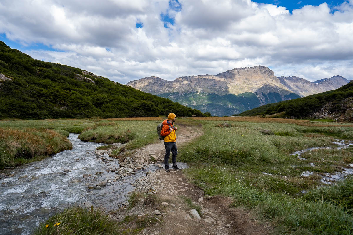 Man standing along a stream with mountains in the background along the Laguna de los Tempanos trail in Ushuaia, Argentina
