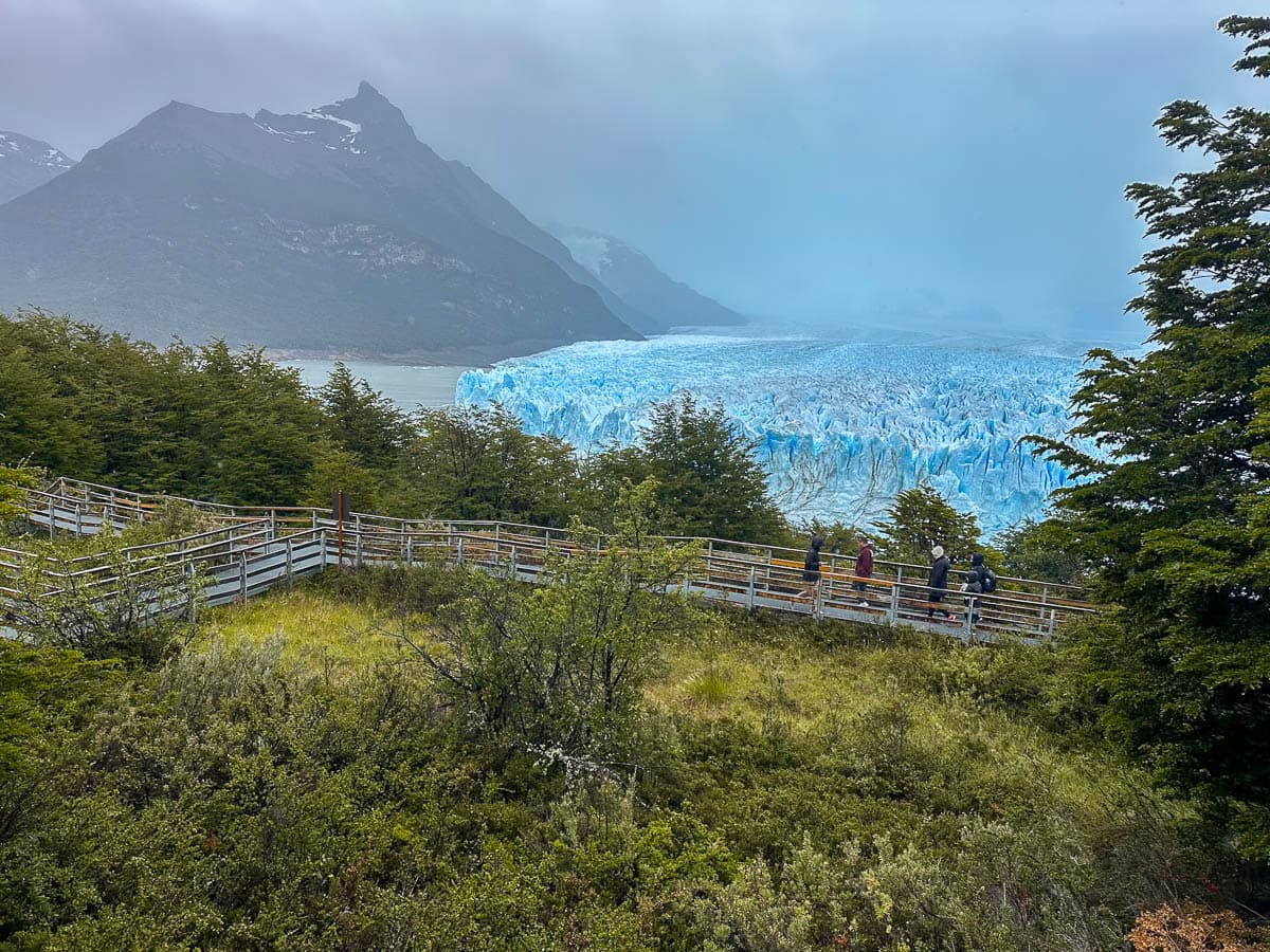 People walking along the metal pathways on the Sendero Inferior with the Perito Moreno glacier in the background in Los Glaciares National Park near El Calafate, Argentina