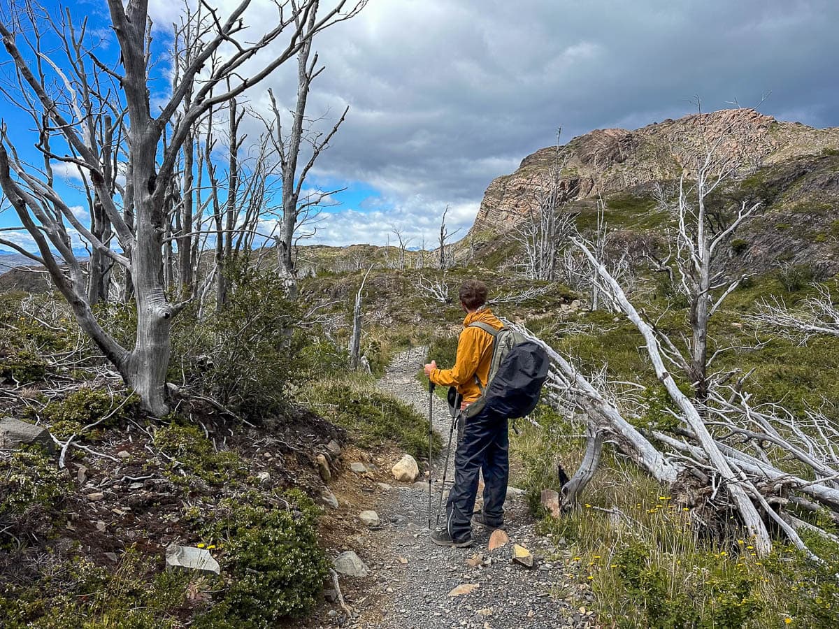 Man walking along the W Trek with a rock formation in the background in Torres del Paine National Park in Chilean Patagonia