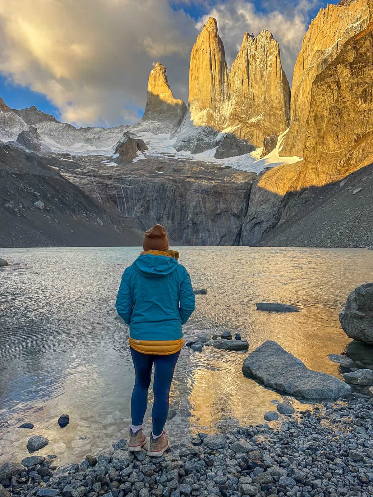 Woman looking at the fiery spires of Torres del Paine at sunrise along the W trek in Torres del Paine National Park in Chilean Patagonia