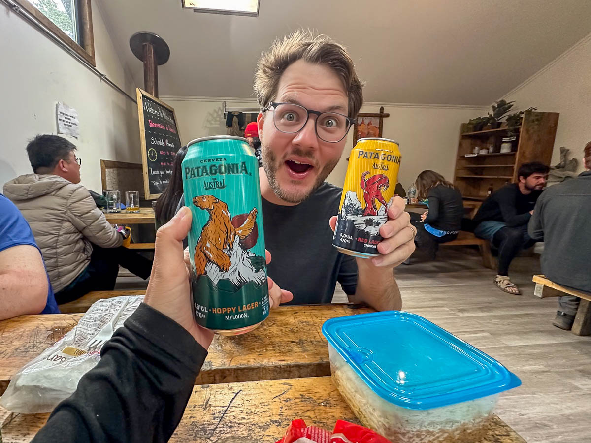 Woman holding a beer in front of a man holding a beer in the dining room of Refugio Cuernos along the W Trek in Torres del Paine National Park in Chilean Patagonia