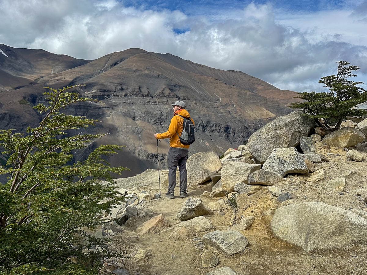 Man standing in front of a brown mountain on a rocky trail on the W Trek in Torres del Paine National Park in Chilean Patagonia