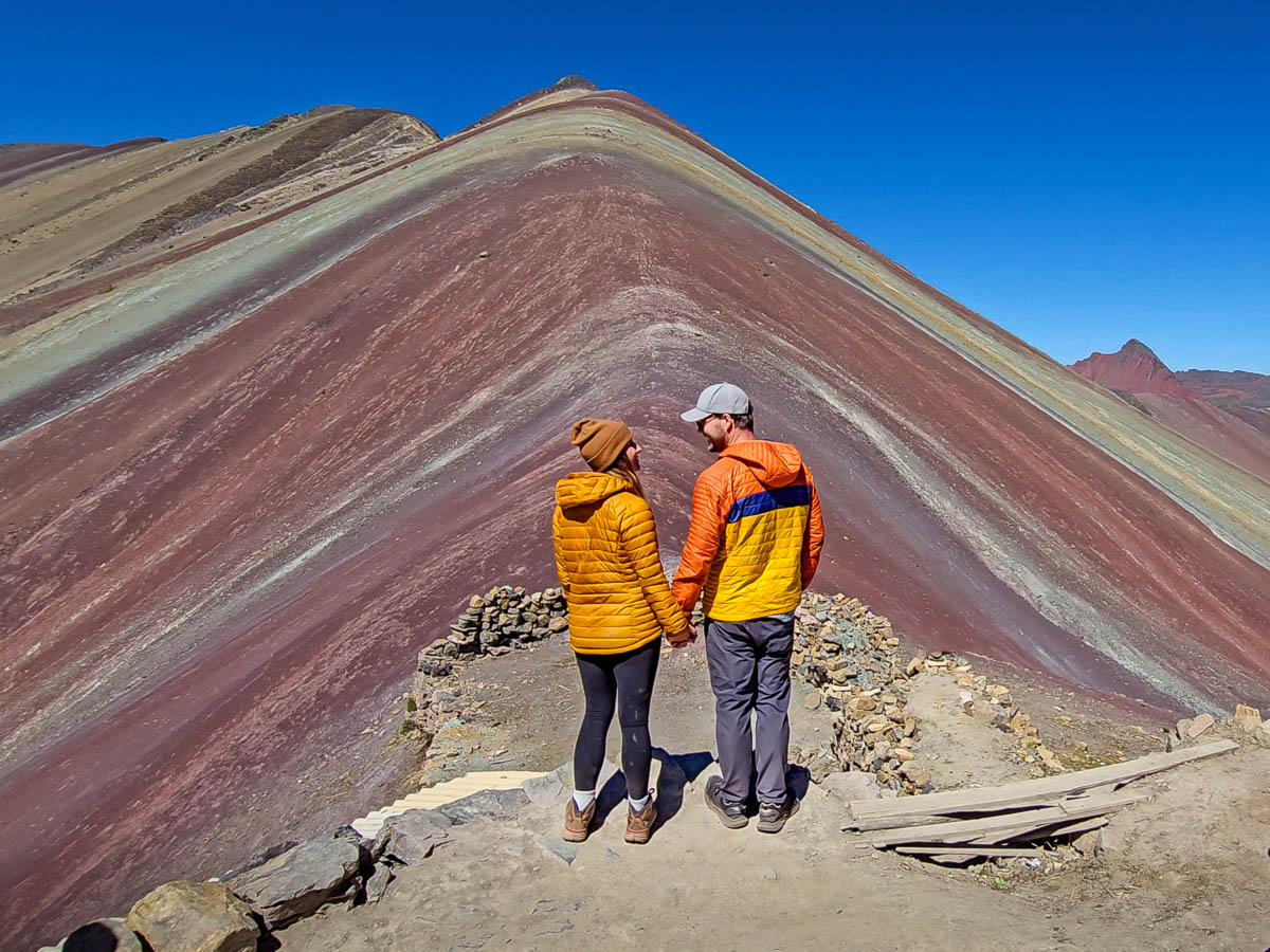Couple standing at the viewpoint of Rainbow Mountain in Peru