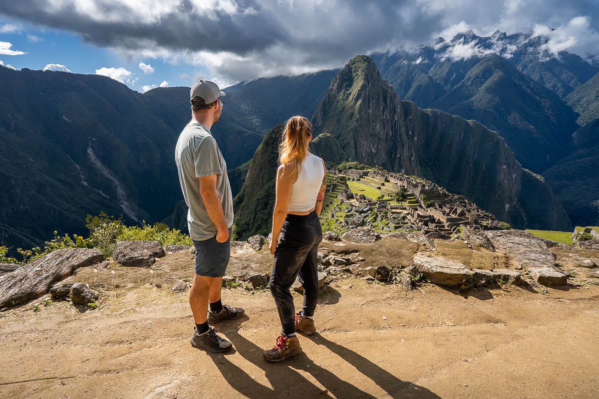 Couple standing at a viewpoint for the ancient Incan city of Machu Picchu in the background of Peru