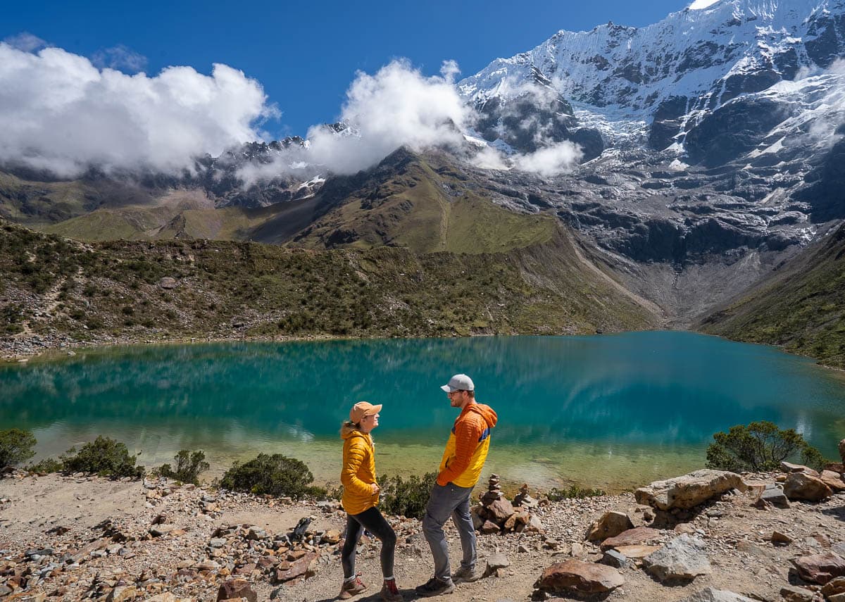 Couple standing on the shores of Humanty Lake with a glacier in the background along the Salkantay Trek in Peru