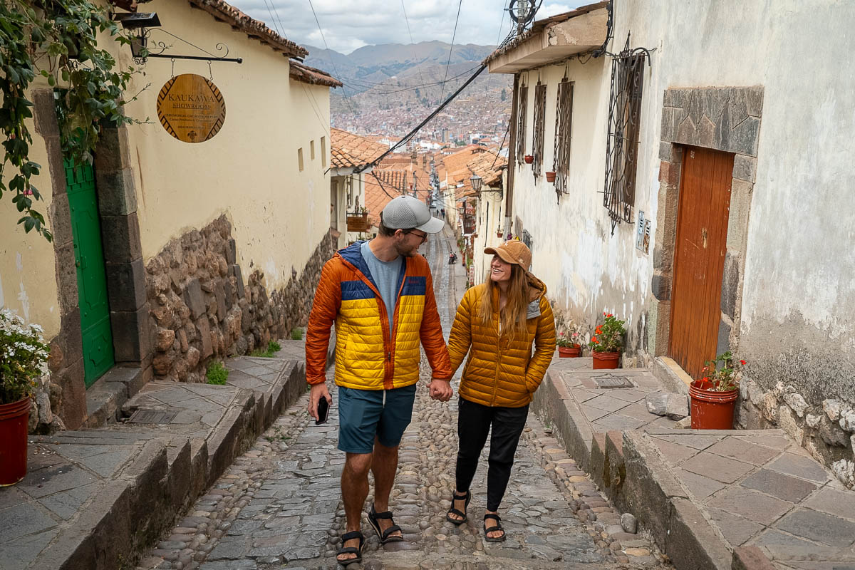 Couple holding hands and walking up a cobblestone street in the San Blas neighborhood of Cusco, Peru