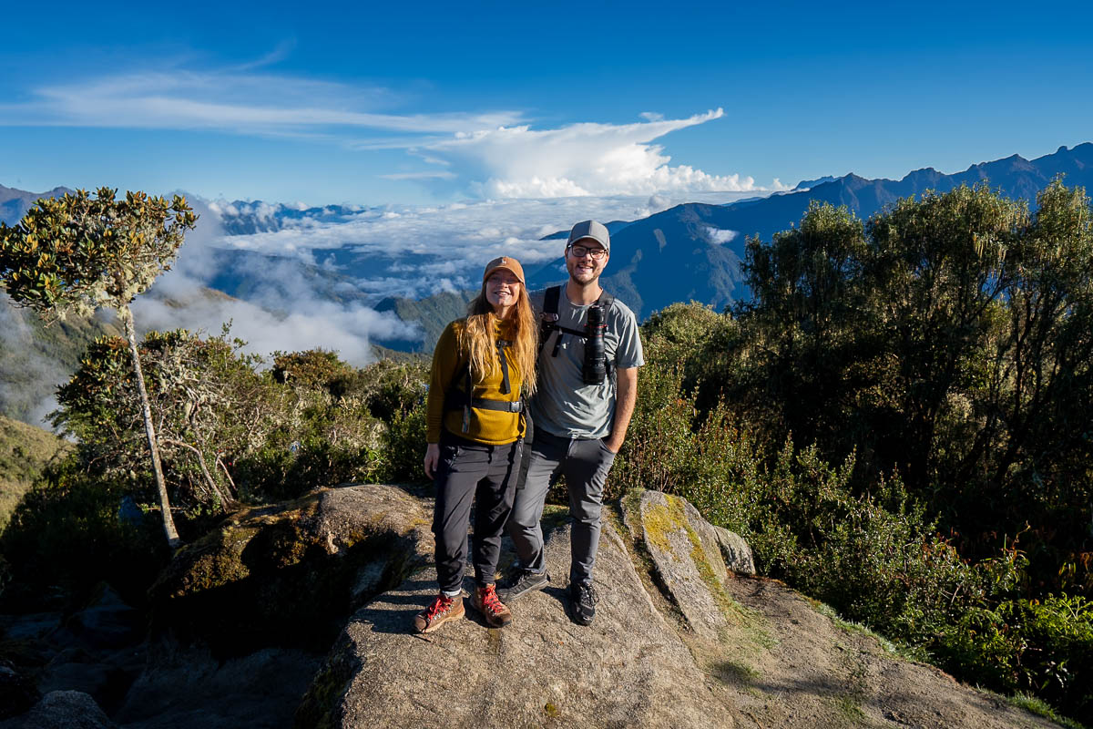 Couple smiling while standing on a rock with Andes mountains in the background at Phuyupatamarca along the Inca Trail in Peru
